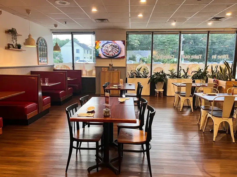 Bright dining area with plant dividers and white cafe chairs by the windows
