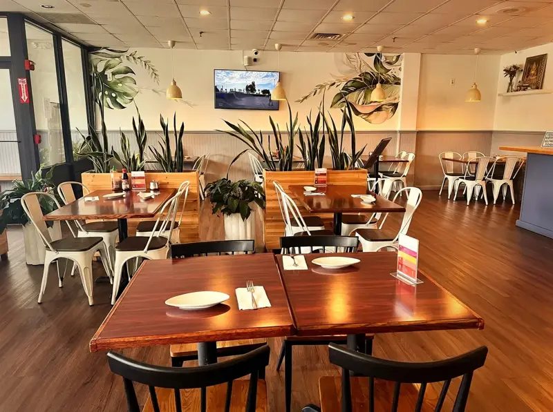 Warm dining room with red booths, wood tables and hanging pendant lights